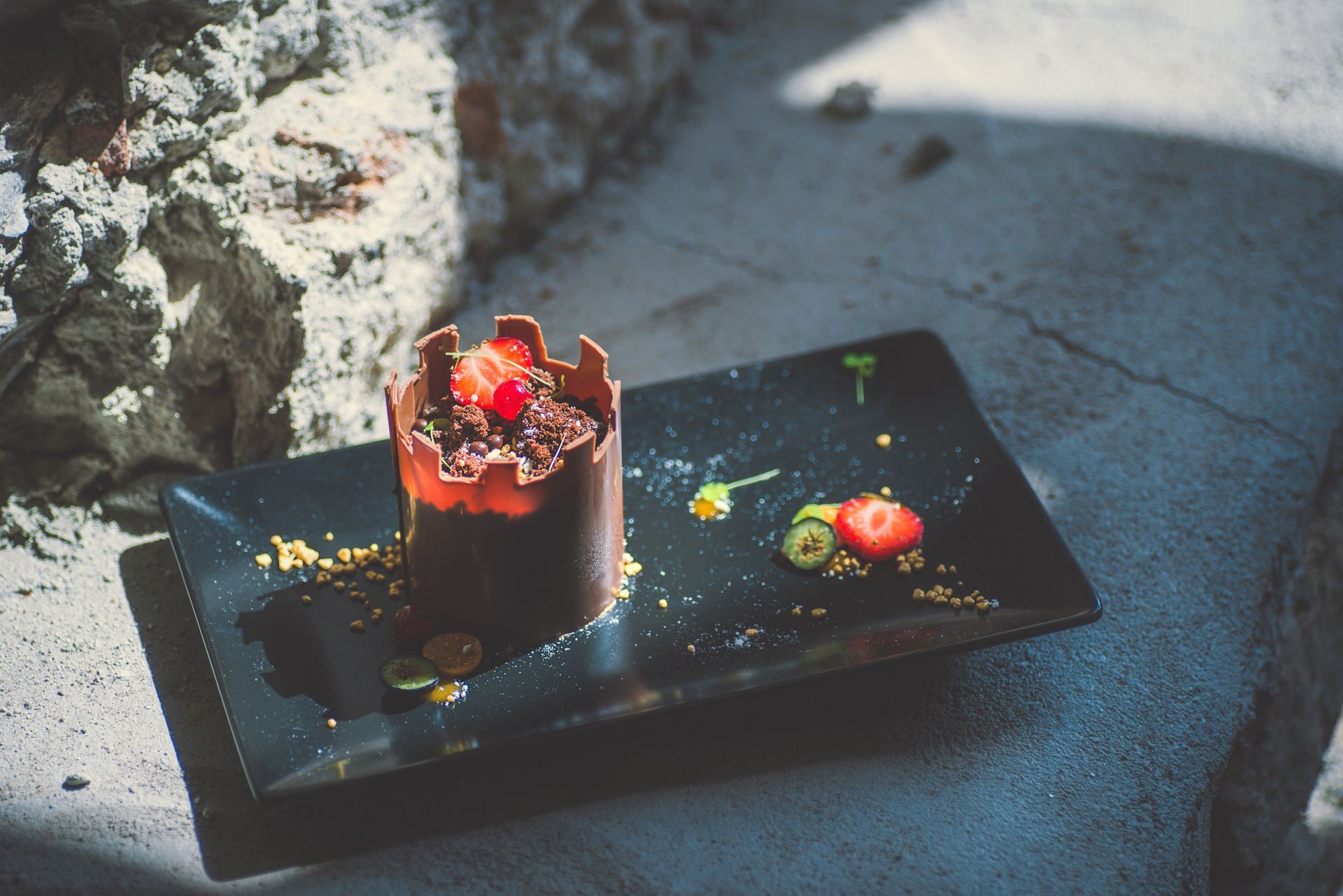 exclusive chocolate cake like tower with fruits served on black plate, product photography for patisserie, dessert for castle 