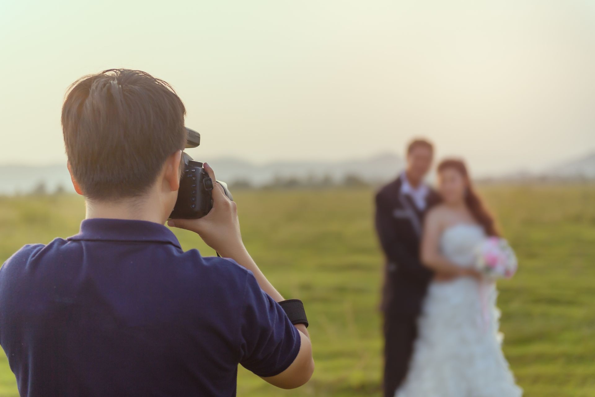 wedding photographer in action, wedding photographer takes pictures of the bride and groom in nature. Behind the scene of photogrphy working concept.